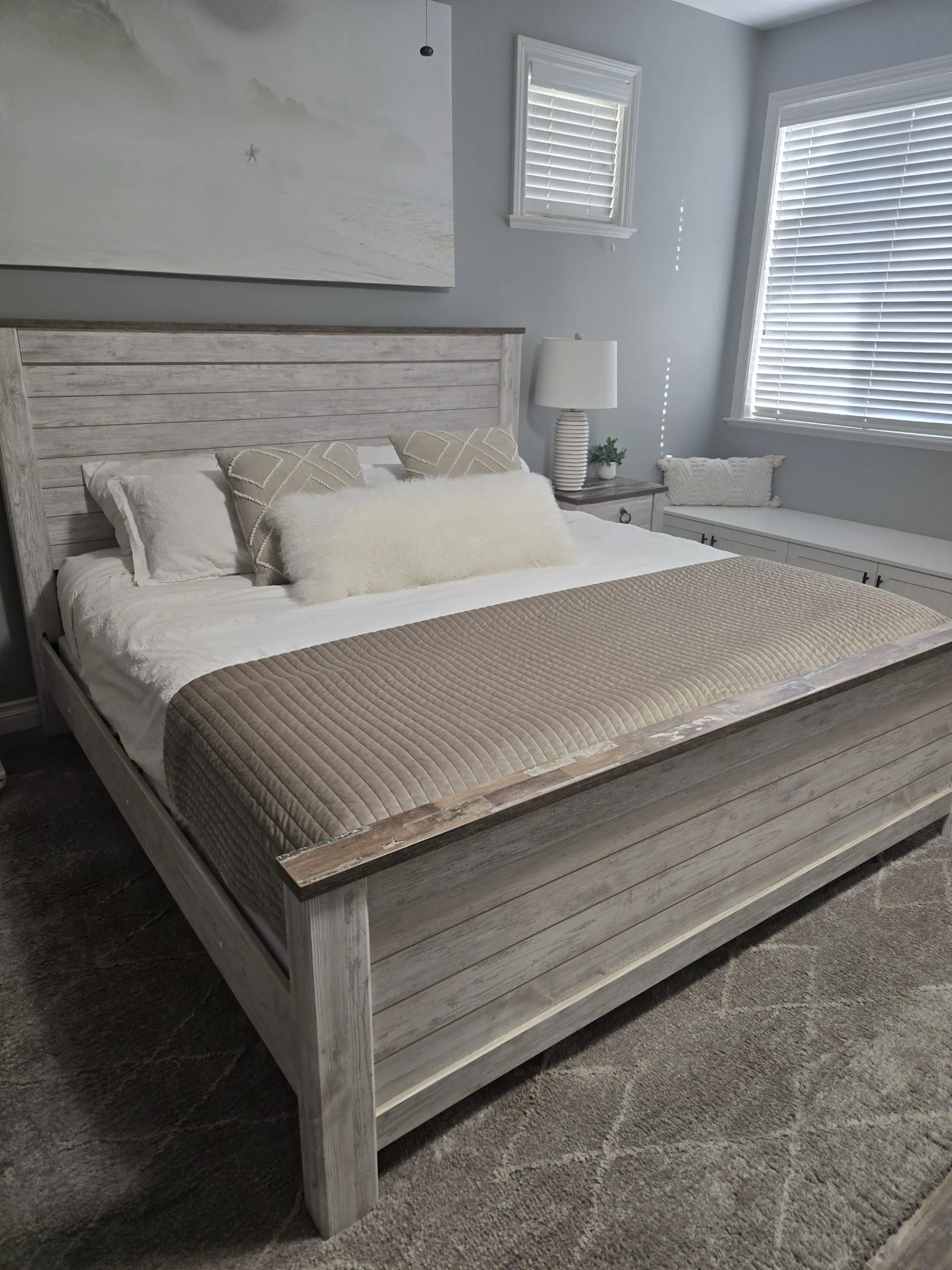 A neatly made bed features soft pillows and a textured blanket in a bright room