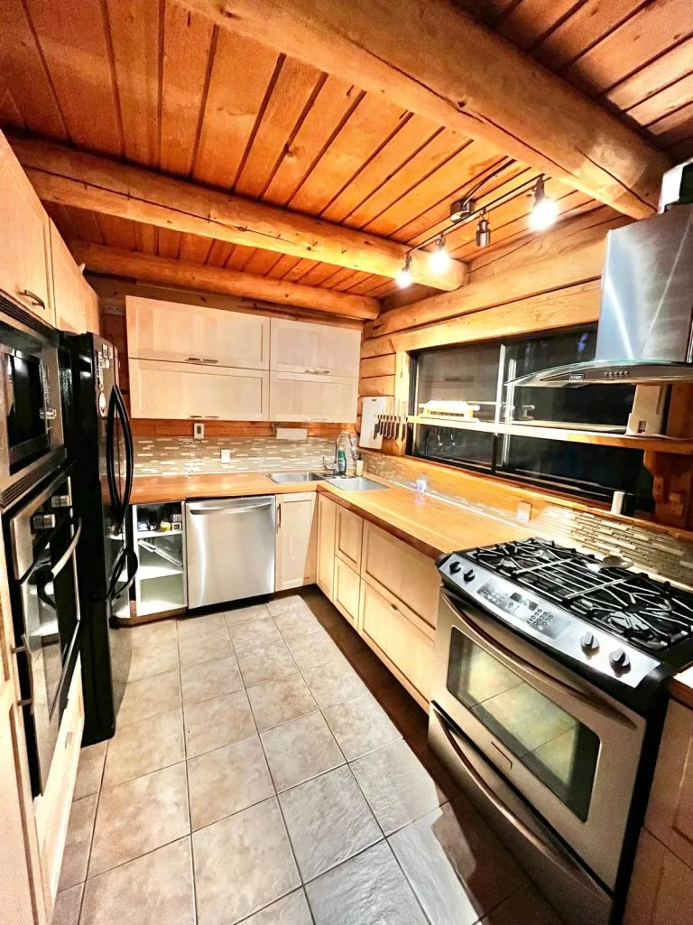 A cozy kitchen features wooden beams, modern appliances, and warm lighting