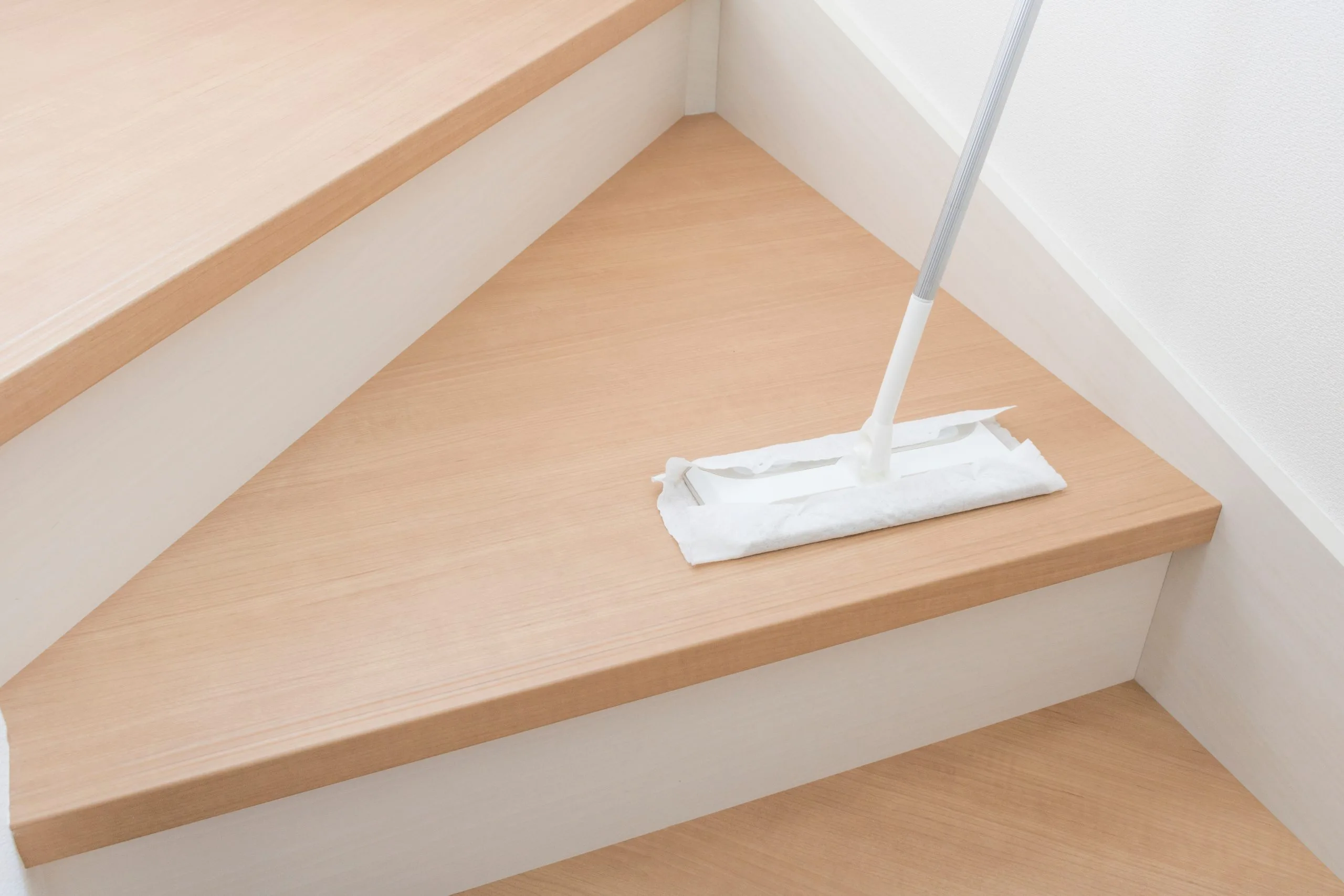 A cleaning mop glides over wooden staircase steps