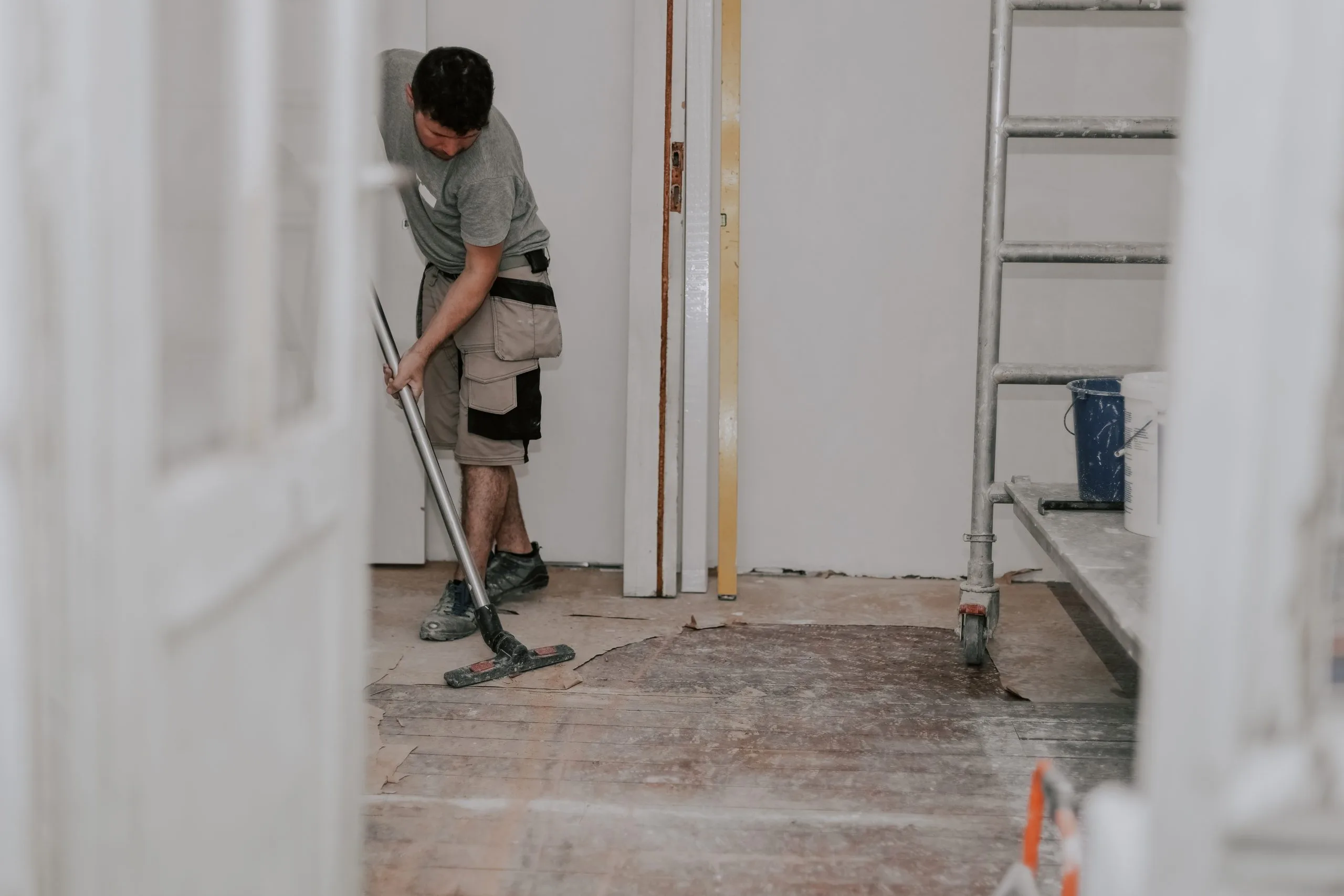 A worker vacuum cleans up debris in a renovated room